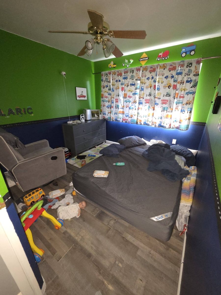 A boy's bedroom with a bare mattress and toys across the floor before cleaning