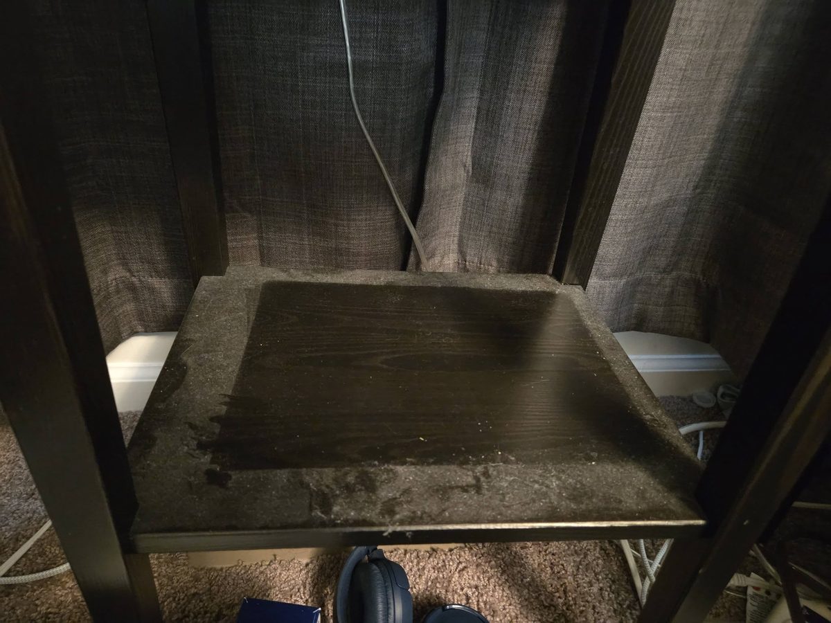 A dark wooden shelf covered in crumbs and debris before cleaning