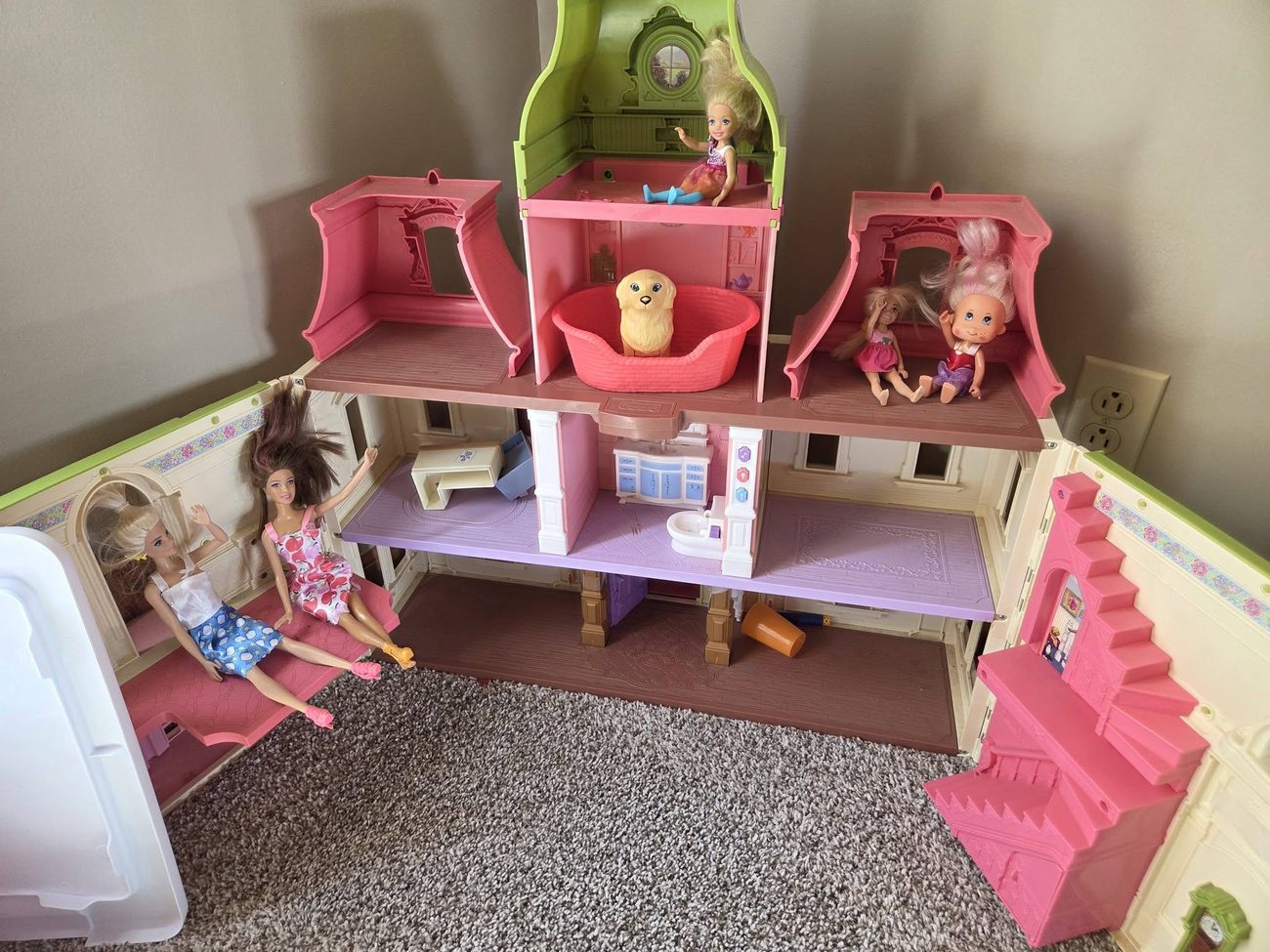 A doll house and toys tidied and arranged in a playroom